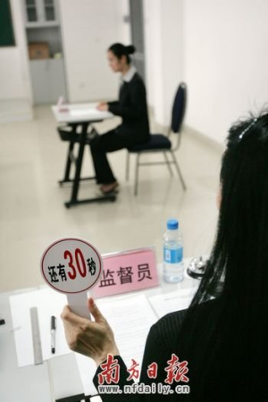 考場監(jiān)督員舉起限時牌提醒考生答題剩余時間。南方日報記者魯力 攝